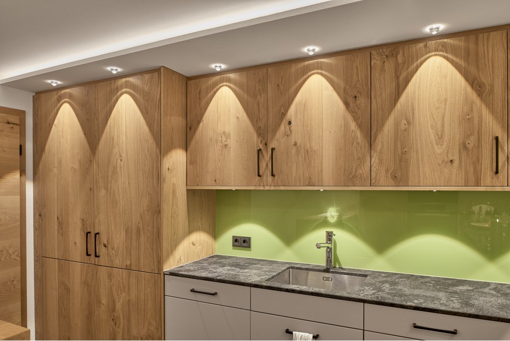 Küchenfront aus Holz perfekt mit Heimatlicht LED Spots ausgeleuchtet mit Lichtspiel an Wänden und Einbauschränken