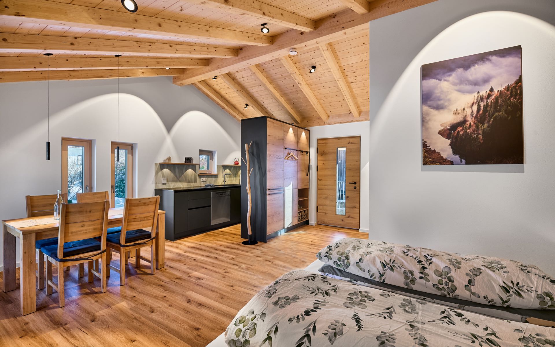 Ein Blick in die harmonisch beleuchtete, kleine Ferienwohnung Heimatgefühl, beleuchteter freier Dachstuhl, offene Küche mit Esstisch.